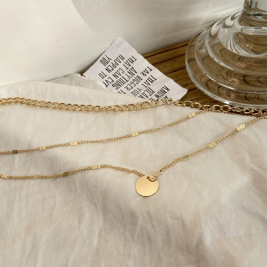 Women's multilayer disc pendant clavicle necklace in gold and silver colour finish on a light background