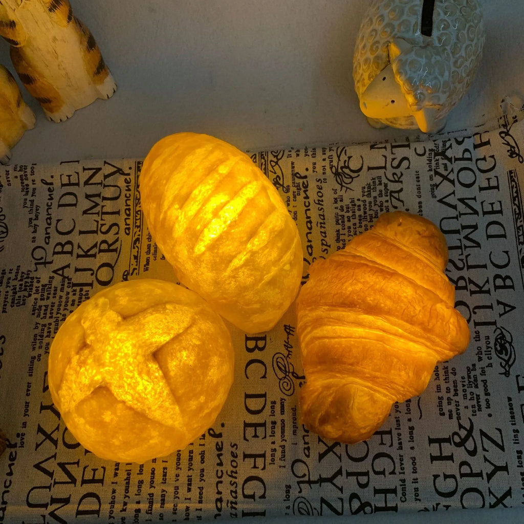 Creative croissant-shaped white LED night light with button switch on a wooden desk.