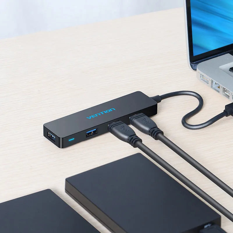 Black four-port USB 3.0 hub with a short cable on a white background.