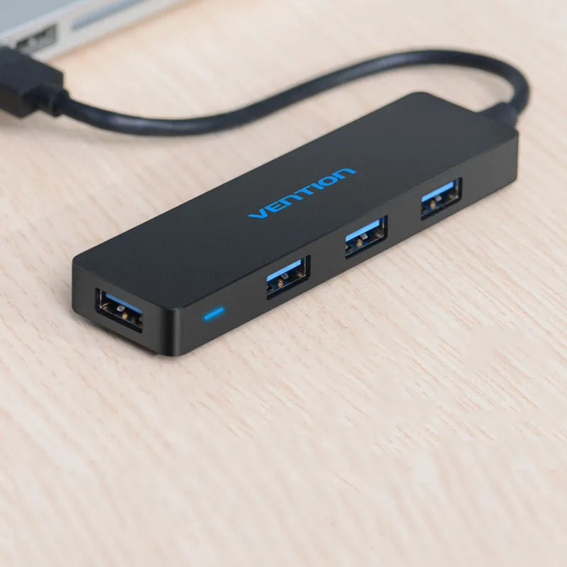 Black four-port USB 3.0 hub with a short cable on a white background.
