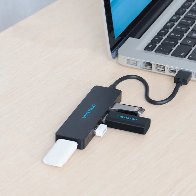 Black four-port USB 3.0 hub with a short cable on a white background.