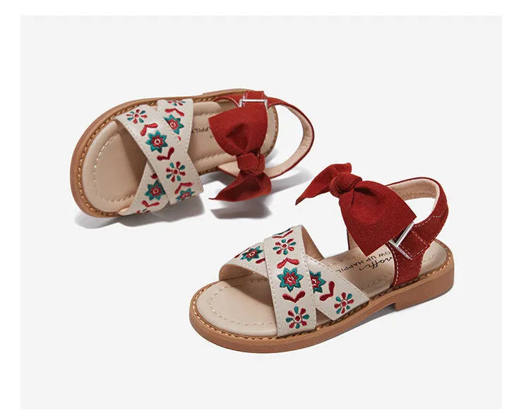 Red girls' soft-soled floral shoes with bow detail and Velcro strap, side view