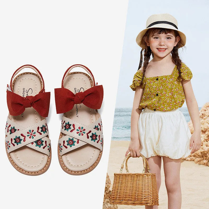 Red girls' soft-soled floral shoes with bow detail and Velcro strap, side view