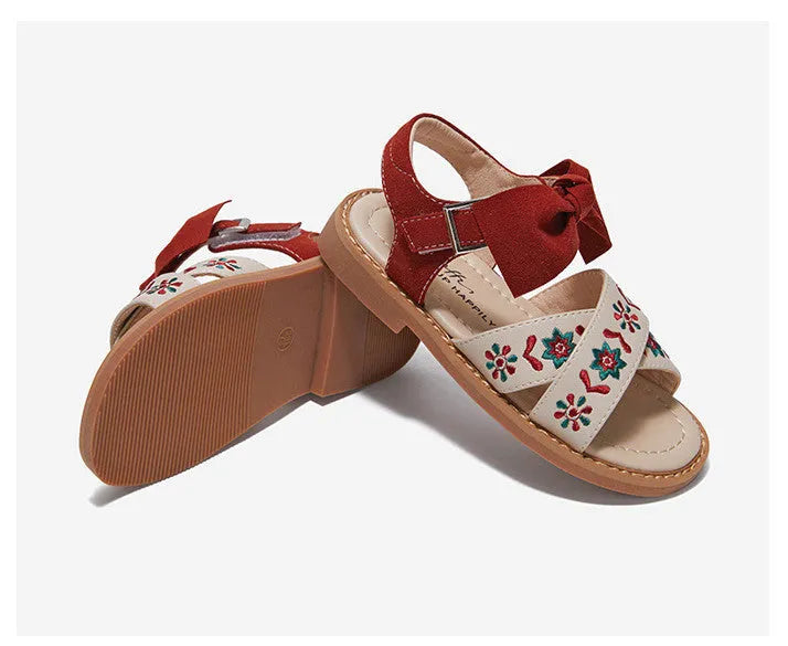 Red girls' soft-soled floral shoes with bow detail and Velcro strap, side view