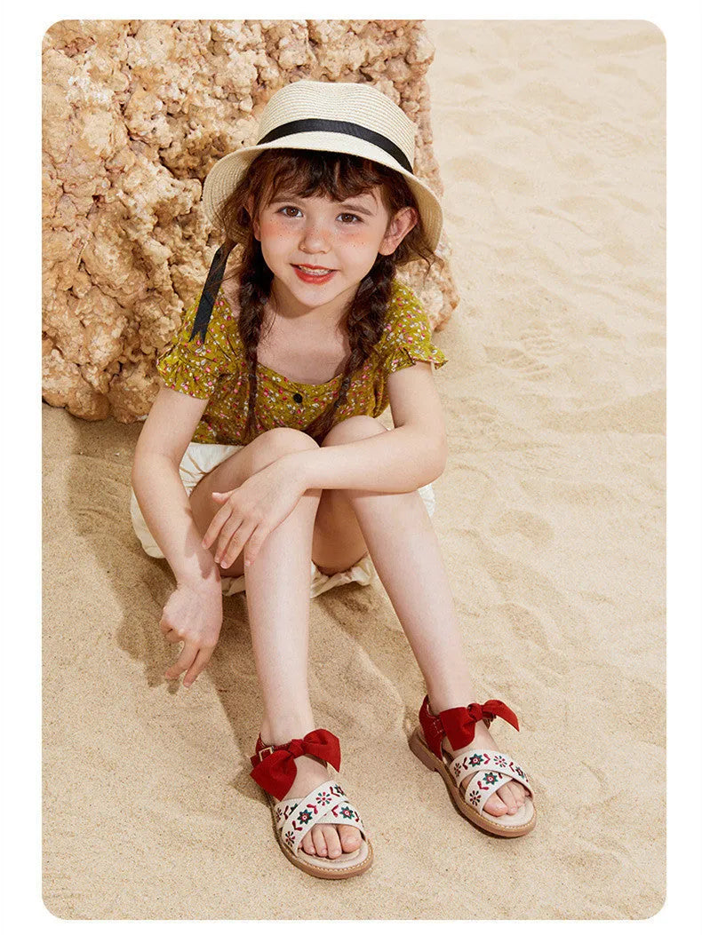 Red girls' soft-soled floral shoes with bow detail and Velcro strap, side view