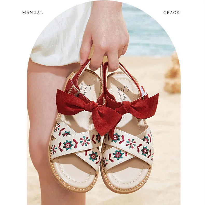 Red girls' soft-soled floral shoes with bow detail and Velcro strap, side view