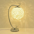Small LED night light with cloth shade in warm glow on wooden table