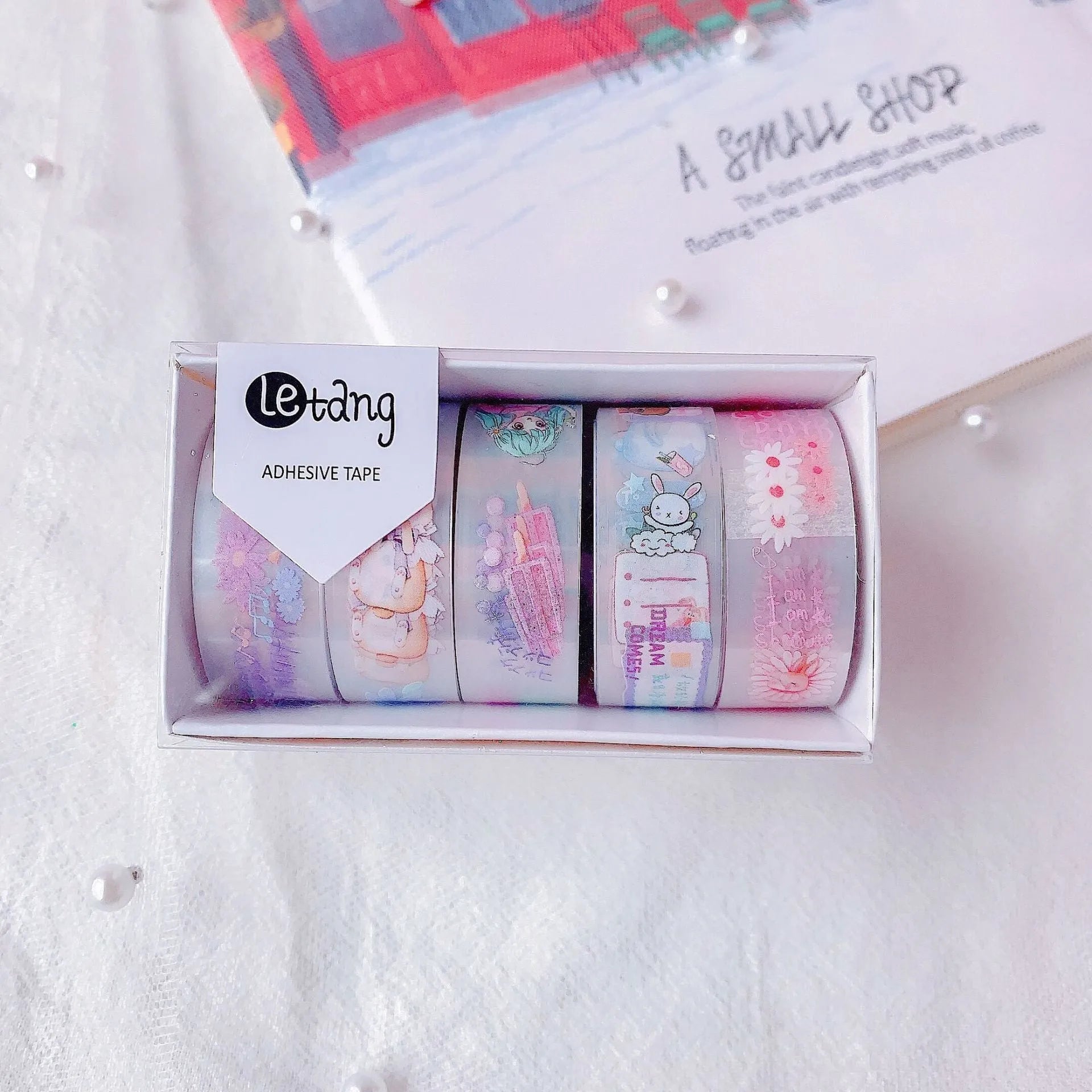 Five rolls of decorative washi tape showing dinosaur, duck, rabbit, and lucky cat designs for craft projects