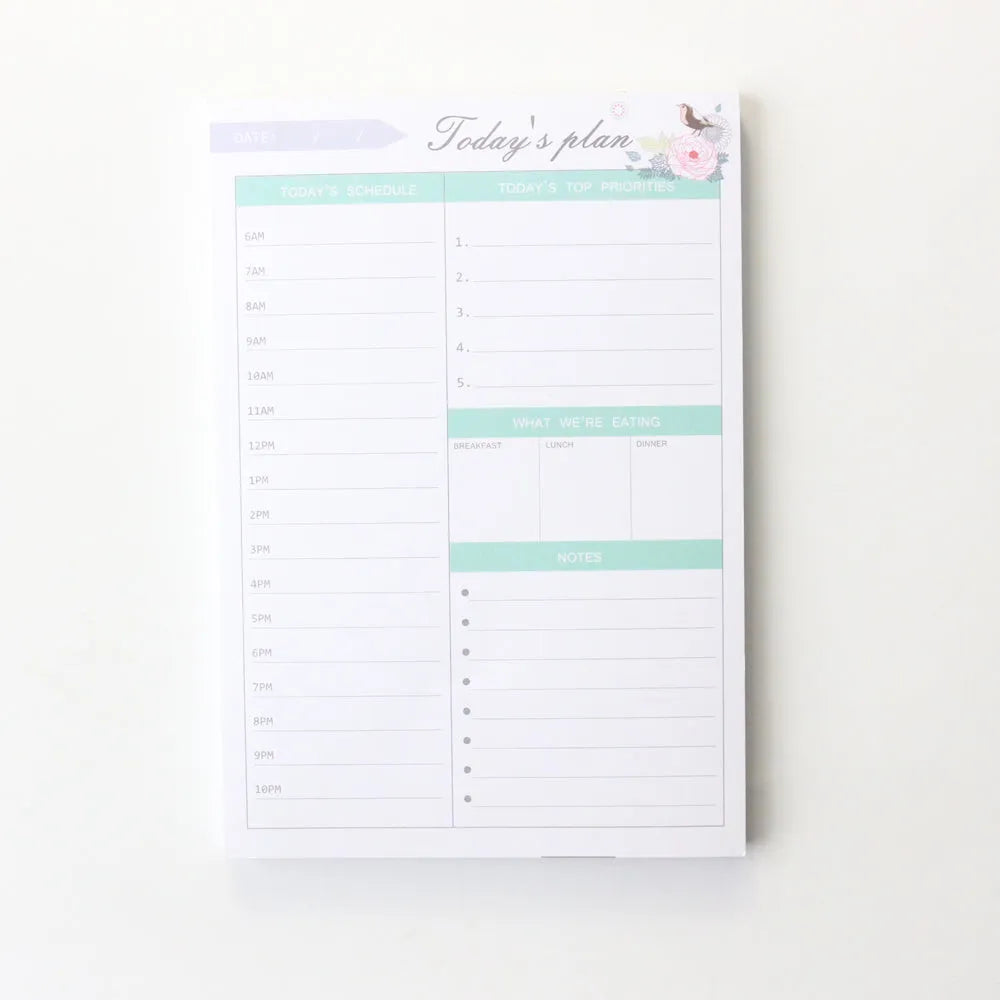 Domikee student desk organiser pad open to show weekly and monthly planning pages in pink and green.