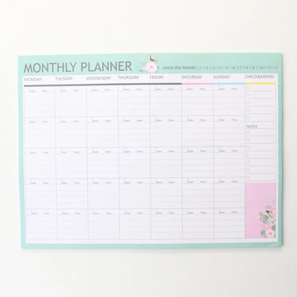 Domikee student desk organiser pad open to show weekly and monthly planning pages in pink and green.