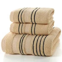 Set of one white 70x140cm cotton bath towel and two smaller grey hand towels on a bathroom shelf.