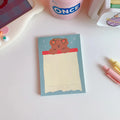 Kawaii cartoon bear design memo pad notebook open on a desk with a pen.