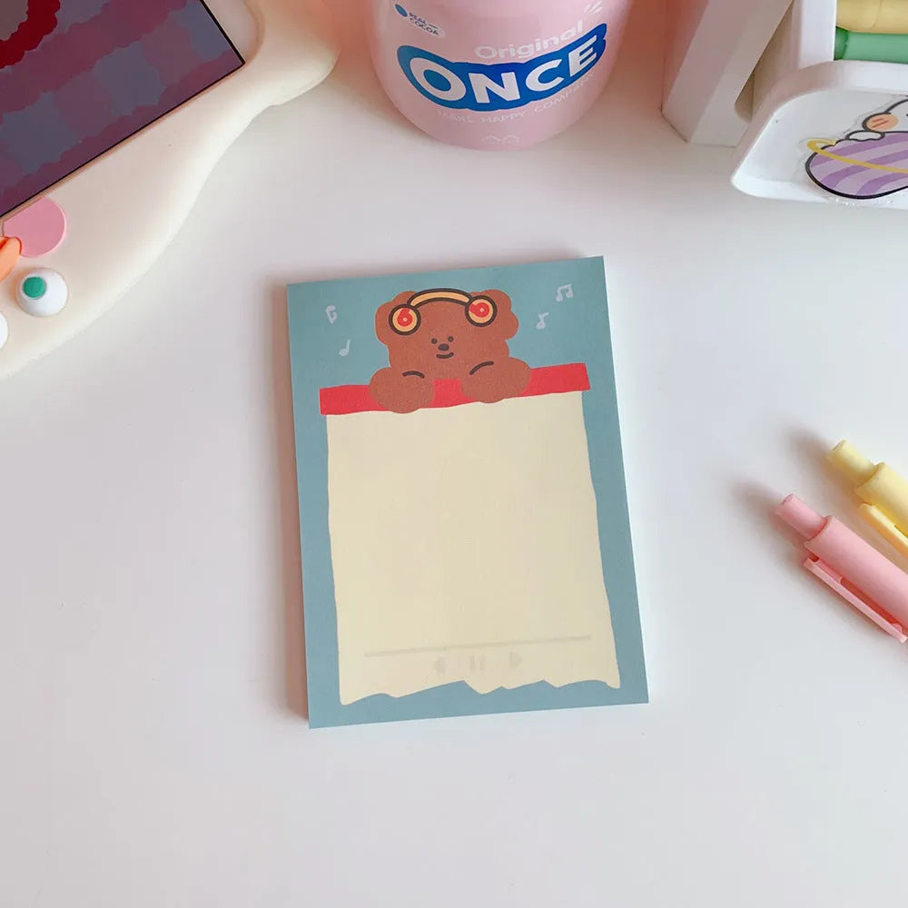 Kawaii cartoon bear design memo pad notebook open on a desk with a pen.
