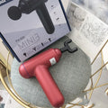 Grey, red, and black fascia massage gun with USB charging port.