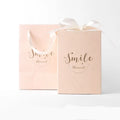Small rigid cardboard gift box with bronzing detail, matching handbag, and raffia bow in four colour options.