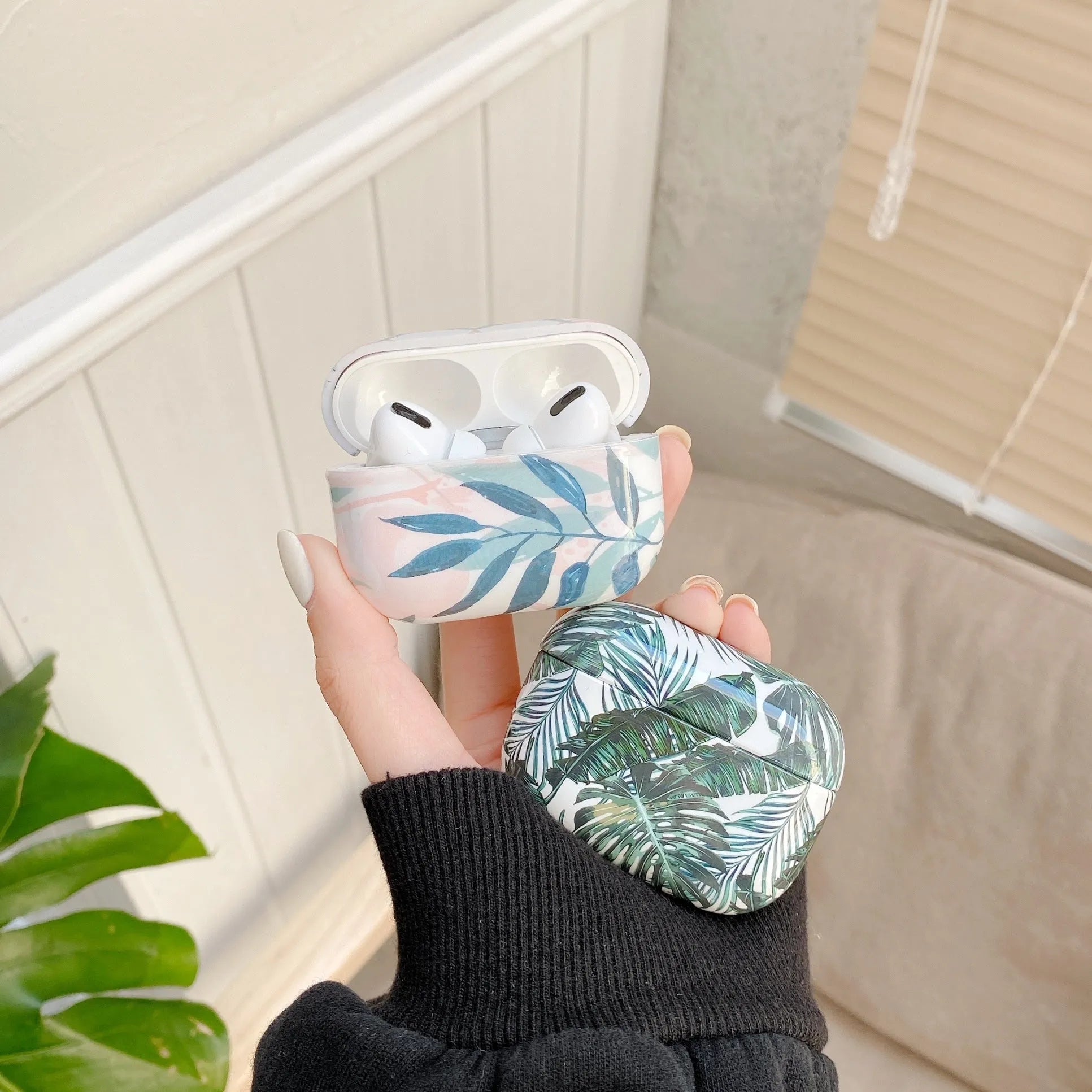 Blue and green TPU AirPods cases featuring a painted tropical banana leaf design.