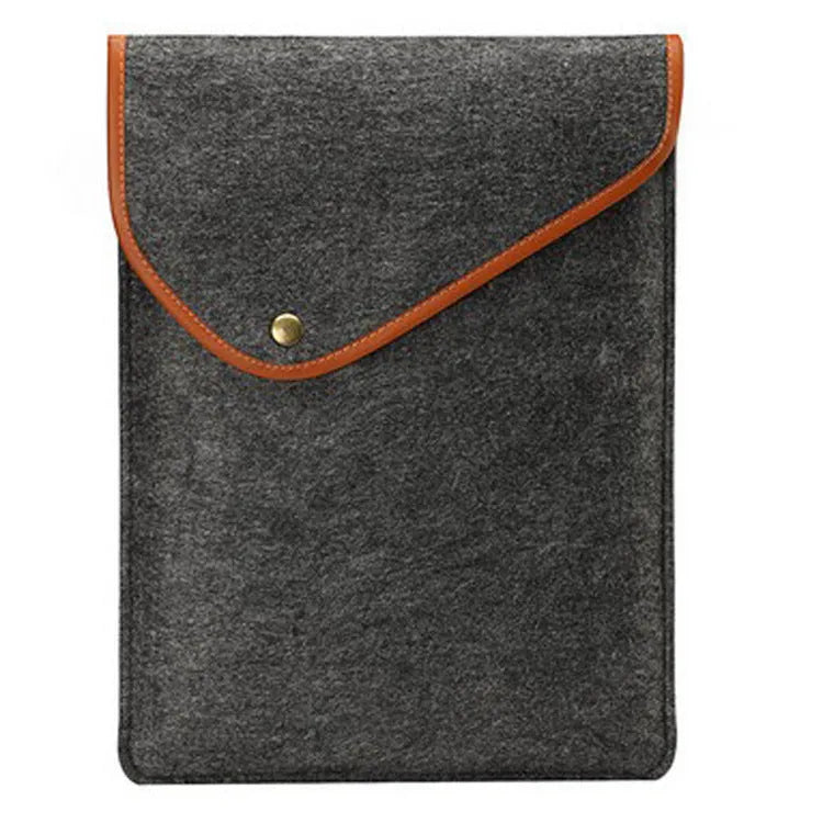 Flat felt bag computer bag in dark grey with magnetic buckle closure on a flat surface