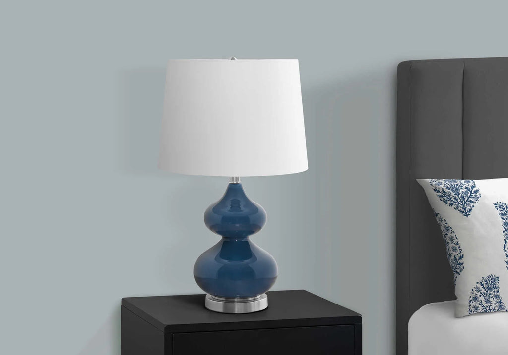 Blue crystal glass desk lamp with a white fabric shade on a wooden desk.