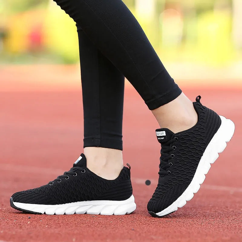 Women's running shoes in black with a fly weave upper and durable outsole.