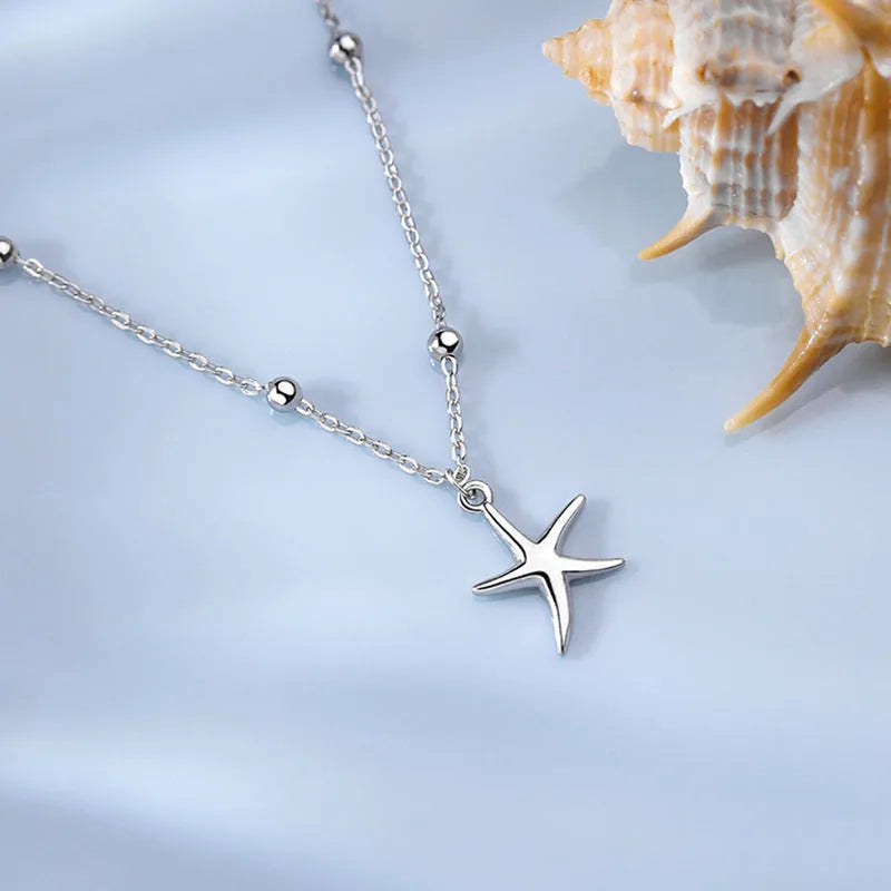 Sterling silver anklet with a starfish charm and round beads on a white background.