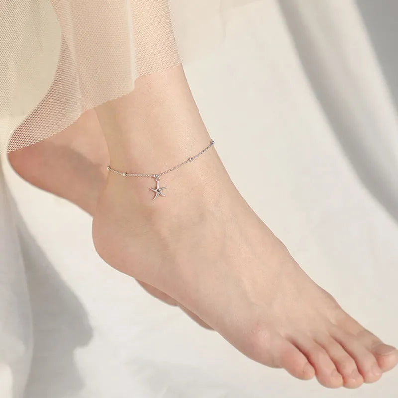 Sterling silver anklet with a starfish charm and round beads on a white background.