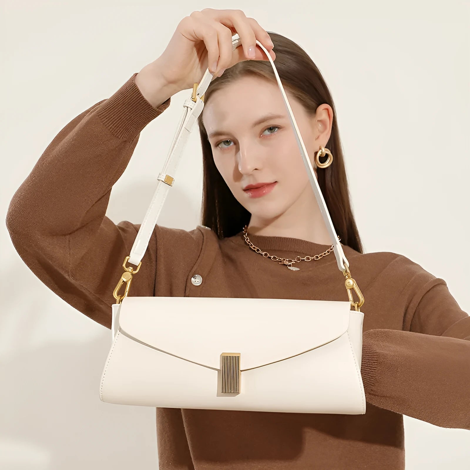 Women's cowhide leather cross-body bag in pillow shape with clamshell opening, shown in milky white colour