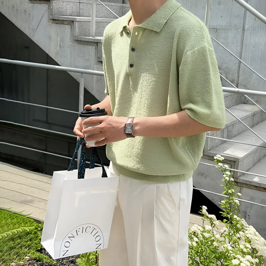 Man modelling a caramel coloured loose-fit knitted short sleeve polo shirt with an asymmetric design.