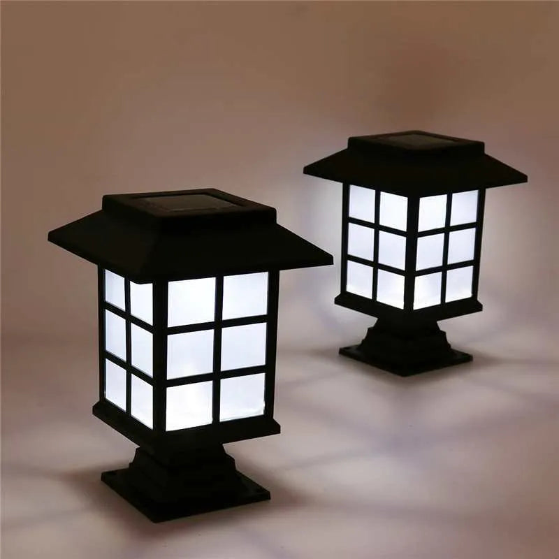 Black solar-powered outdoor LED lawn light with window-style openings, shown in a garden setting.