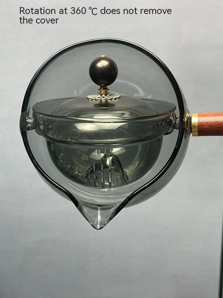 Transparent rotary glass teapot with wooden handle and built-in infuser on countertop