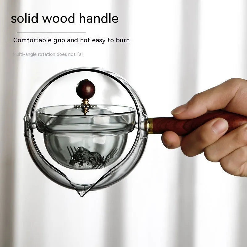 Transparent rotary glass teapot with wooden handle and built-in infuser on countertop