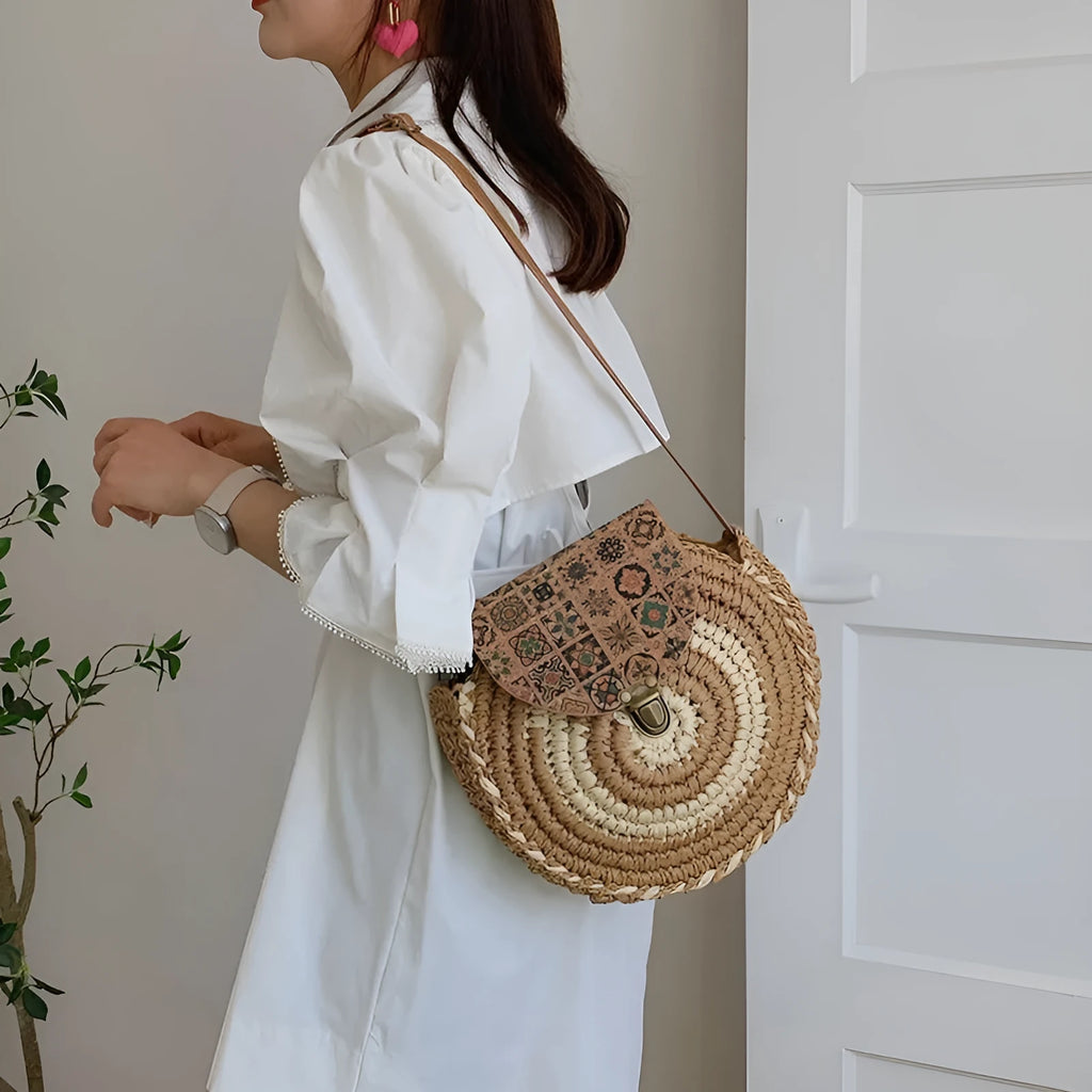 Round straw woven crossbody bag in beige, 25cm diameter, with adjustable shoulder strap, displayed on a neutral background