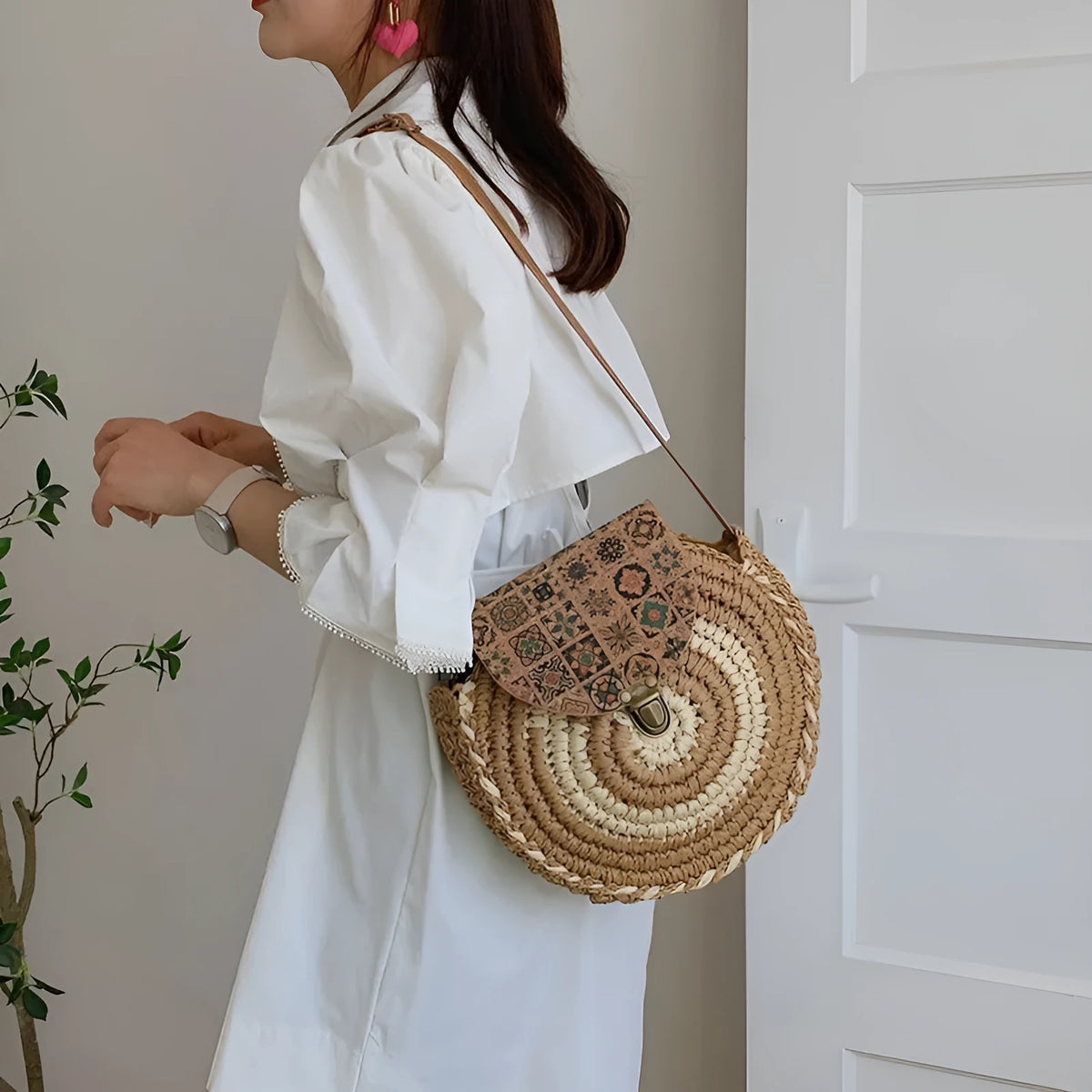Round straw woven crossbody bag in beige, 25cm diameter, with adjustable shoulder strap, displayed on a neutral background