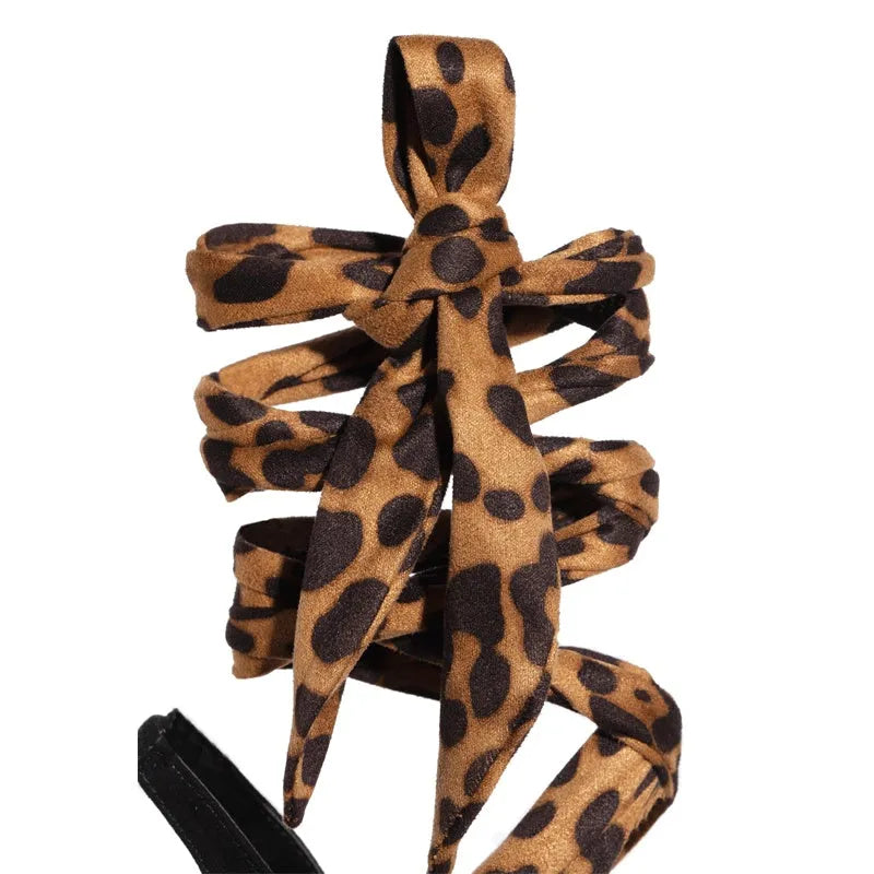 Light brown leopard print women's high-heeled sandals with cross straps and a stiletto heel.