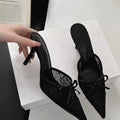 Women's light brown lace high heels with a pointed toe and a black bowknot detail on the front.