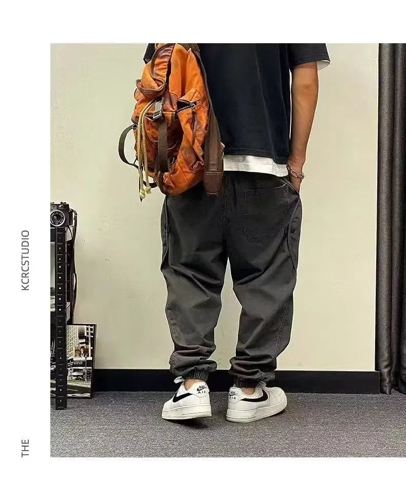Men's black cotton harem pants with elastic waist and drawstring, cropped ankle bandage leg, side view