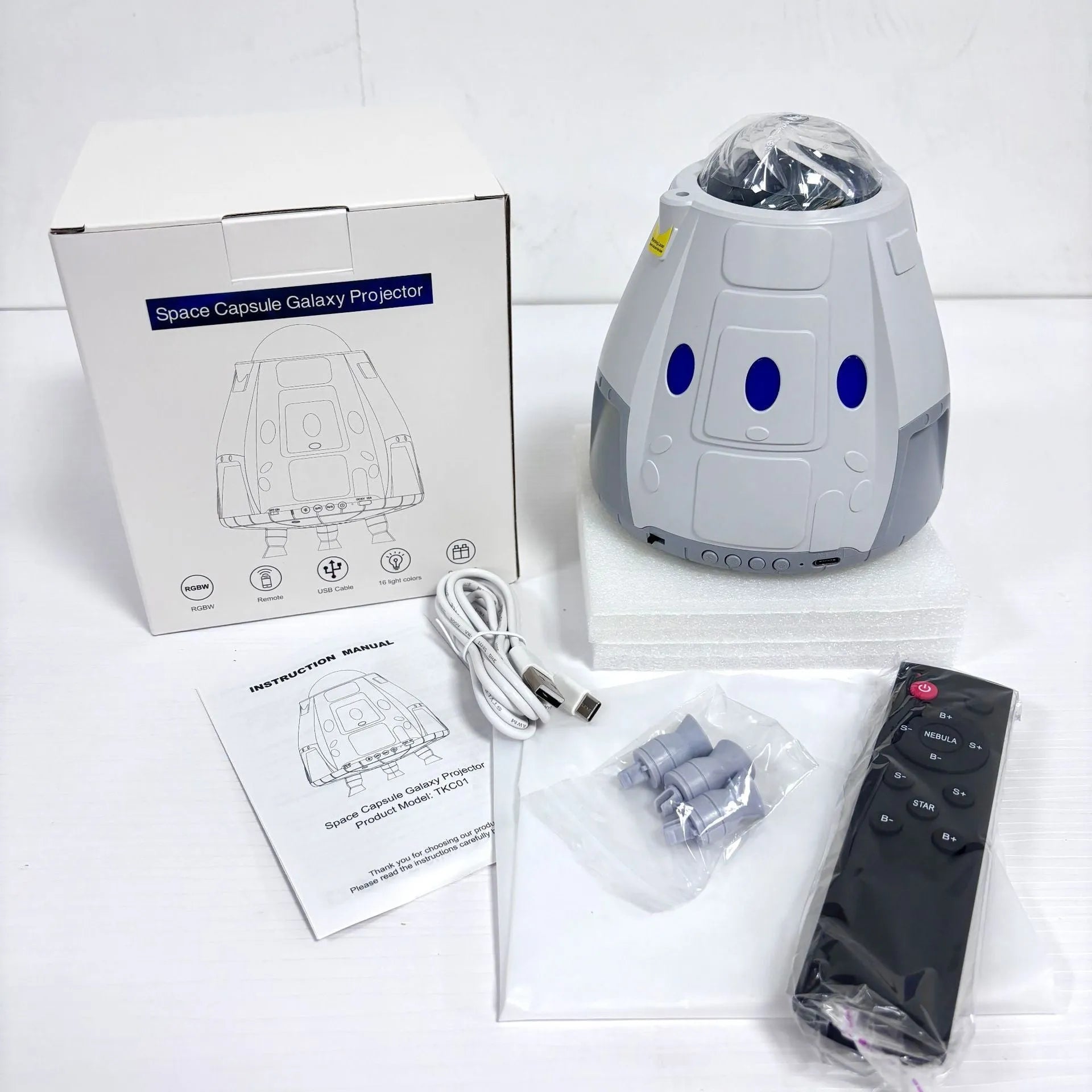 Space capsule shaped galaxy atmosphere projection lamp in white or grey with USB cable and remote.