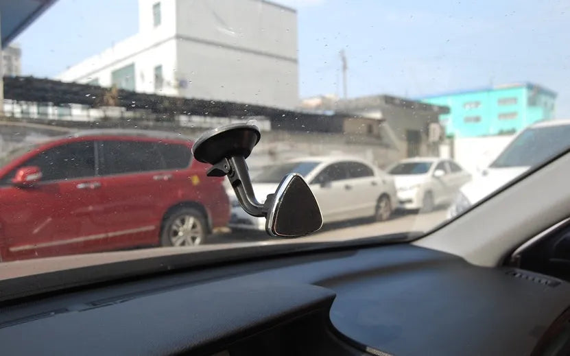 Black magnetic car phone holder mounted on dashboard with phone attached, showing 360-degree rotation capability