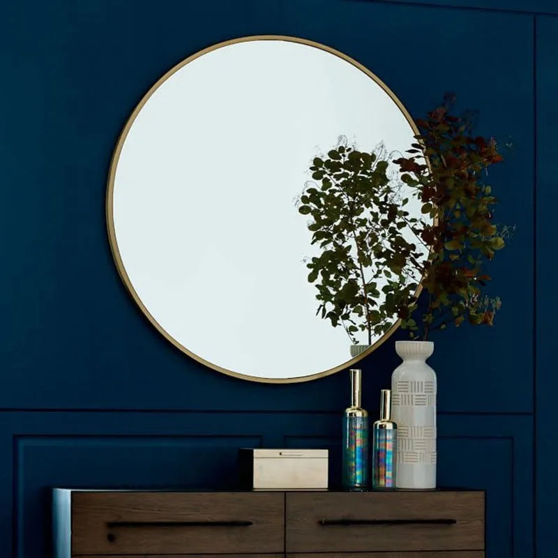 Round metal-framed wall mirror in black, white, or gold, shown in a bathroom setting.