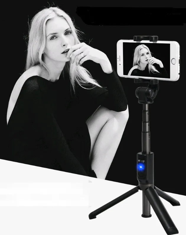 Aluminium telescopic Bluetooth selfie stick with tripod base and remote control next to a smartphone.