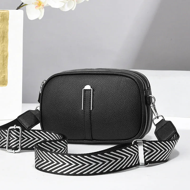 A soft oval-shaped women's crossbody bag in PU leather with a stone pattern texture and a front slit pocket.