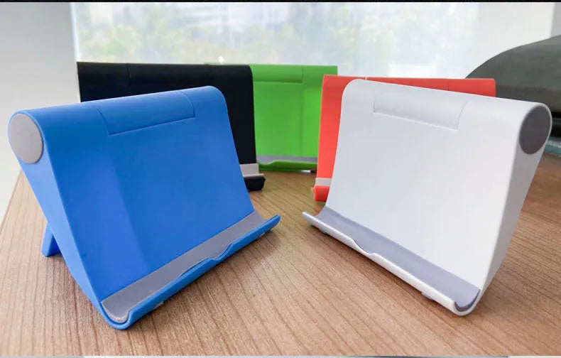 Black PE plastic folding stand holding a tablet at an adjustable angle on a wooden desk.