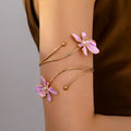 Close-up of a pink alloy armband with a hollow patterned design, shown on a wrist.