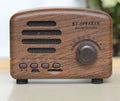 Vintage-style wood-effect Bluetooth speaker in black, pink, and wood grain colour options.