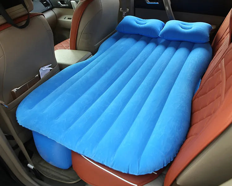 Black inflatable car bed with flocked material set up in the back of a five-seater vehicle, showing two pillows.