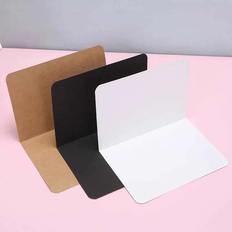 A pack of 100 folded kraft paper greeting cards in 10x15cm size, showing colour options: black, cowhide brown, and white.