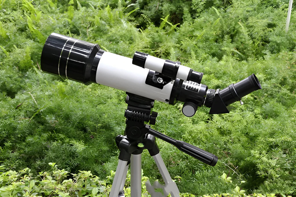 Dark blue and white children's monocular astronomical telescope with tripod on a table.