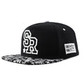 Black and white cotton baseball cap with letter embroidery on the front, showing adjustable strap at back.
