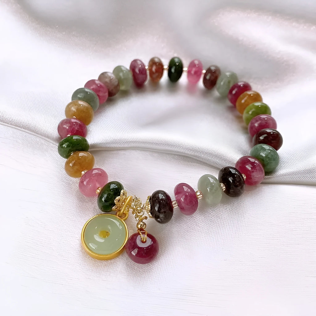 Colourful tourmaline beaded bracelet with geometric abacus beads and a rabbit pendant on a white background.