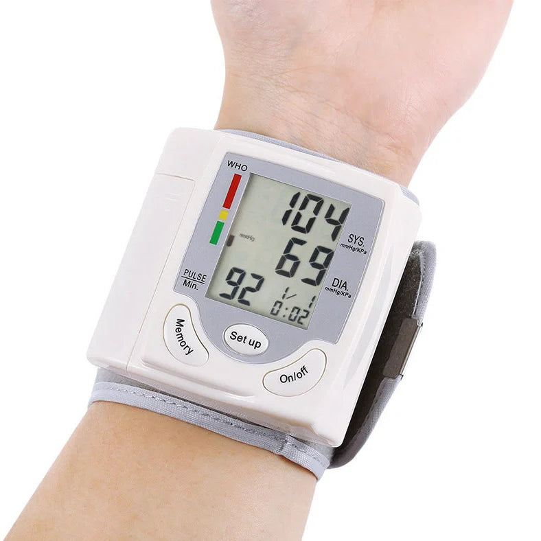 White wrist blood pressure monitor with digital display showing blood pressure readings and adjustable cuff