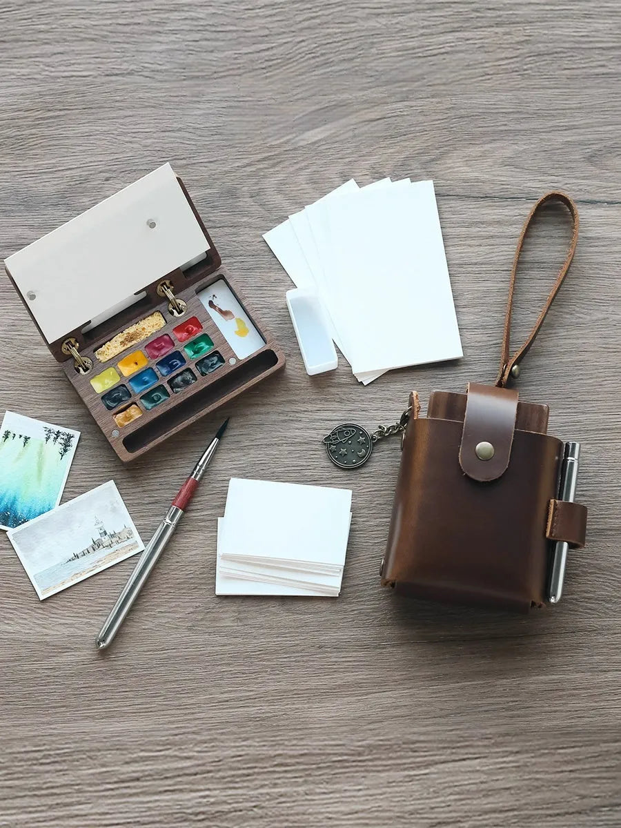 Mini walnut-finish wooden watercolour paint box open to show internal compartments with pigment pans.
